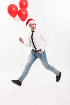 圣诞节概念英俊的业务男人。跳庆祝快乐圣诞节快乐一年穿圣诞老人他红色的气球