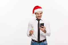 圣诞节概念英俊的业务男人。会说话的电话持有玻璃champange庆祝圣诞一年