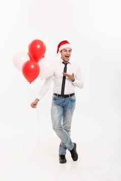 圣诞节概念英俊的快乐业务男人。穿圣诞老人他给红色的气球快乐圣诞节快乐一年穿圣诞老人他