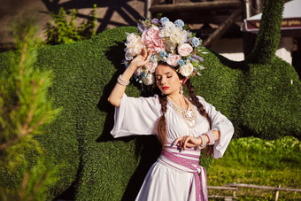 浅黑肤色的女人女孩白色乌克兰真实的国家服装花环花摆姿势绿色雕刻布什