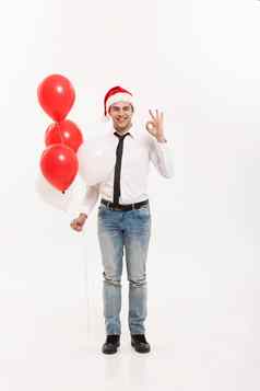 圣诞节概念英俊的快乐业务男人。走红色的气球庆祝快乐圣诞节快乐一年穿圣诞老人他