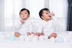 快乐的双胞胎婴儿玩颜色球床上