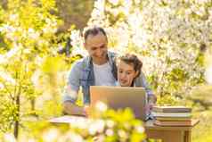 有爱心的年轻的父亲帮助女儿研究看在线教训移动PC细心的爸爸小女孩孩子学习首页网络类电脑检疫户外