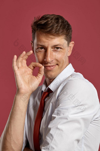 年轻的男人。经典白色衬衫红色的领带摆姿势粉红色的背景