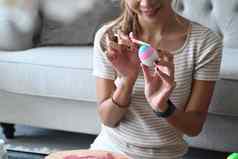 快乐的年轻的女人坐着地板上生活房间着色蛋复活节节日