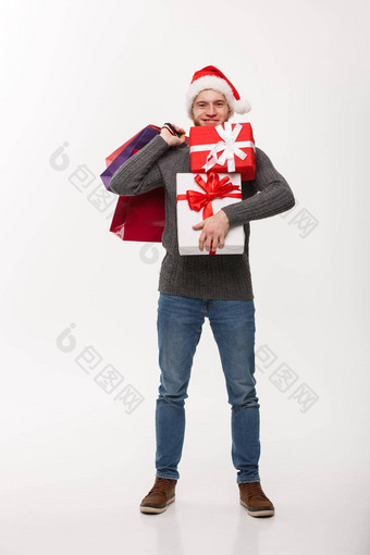 圣诞节概念有吸引力的年轻的高加索人男人。享受购物持有很多礼物圣诞节一天
