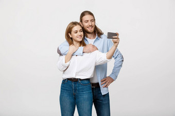 肖像快乐夫妇使自拍照片智能手机孤立的白色工作室背景
