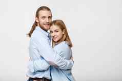 肖像快乐的年轻的夫妇站拥抱孤立的白色背景