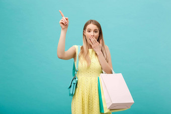 快乐购物年轻的女人手指点复制空间袋孤立的蓝色的背景