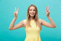 年轻的女人显示手指积极的和平手势白色
