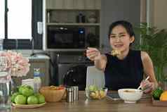 健康的亚洲女人坐着首页厨房享受素食主义者餐饮食健康的食物概念