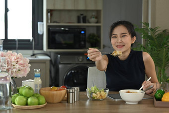 健康的亚洲女人坐着<strong>首页</strong>厨房享受素食主义者餐饮食健康的食物概念