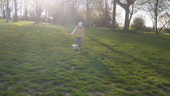 快乐家庭孩子们有趣的春天公园孩子运行孩子女孩运球黑色的白色经典足球球绿色草人玩足球童年体育运动冠军概念