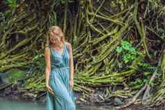 年轻的女人旅行者巴厘岛的花园杂草丛生的莫斯旅行巴厘岛概念