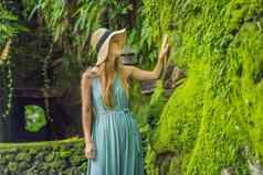 年轻的女人旅行者巴厘岛的花园杂草丛生的莫斯旅行巴厘岛概念