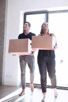 快乐年轻的夫妇携带大纸板盒子