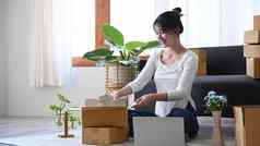 年轻的女人小业务企业家包装产品纸板盒子交付客户在线销售电子商务