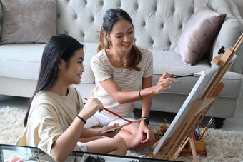微笑亚洲女人年轻的妹妹坐着前面画架绘画图片帆布