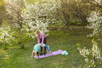 年轻的女人女儿运动统一的瑜伽房子花园
