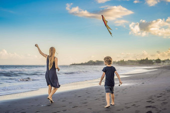 年轻的女人发射风筝海滩<strong>梦想</strong>愿望未来计划