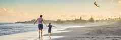 年轻的父亲儿子运行风筝海滩横幅长格式