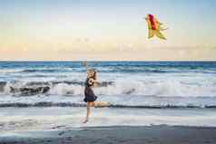 年轻的女人发射风筝海滩梦想愿望未来计划