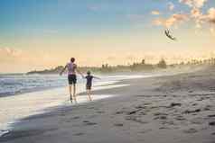 年轻的父亲儿子运行风筝海滩