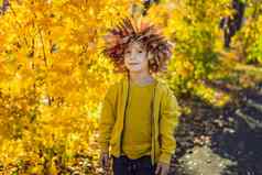肖像微笑孩子花环叶子头背景阳光明媚的秋天公园