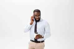 肖像困惑年轻的非洲男人。穿着白色衬衫会说话的移动电话手势孤立的白色背景