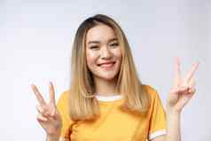 快乐年轻的亚洲女人显示手指胜利手势空白Copyspace区域文本肖像美丽的亚洲女人孤立的白色背景