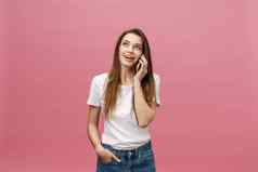 快乐的年轻的女人会说话的移动电话孤立的粉红色的背景