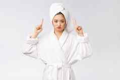 年轻的美丽的女人穿淋浴毛巾浴孤立的白色背景指出手指