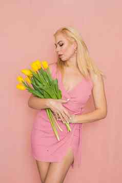 金发女郎粉红色的夏天衣服持有花束黄色的郁金香