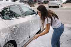 有吸引力的年轻的女人洗车洗发水刷女洗汽车泡沫水服务车洗