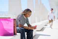 黑色的女人智能手机坐着板凳上街