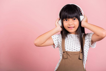 亚洲孩子年微笑听音乐穿无线耳机头