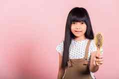 亚洲孩子年持有梳子刷牙不守规矩的触碰长黑色的头发