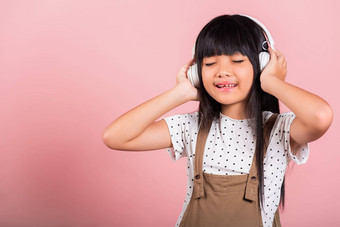 亚洲孩子年微笑听音乐穿无线耳机
