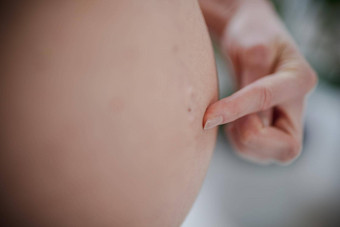 怀孕了女人肚子怀孕概念怀孕了肚子关闭手指指出肚子按钮