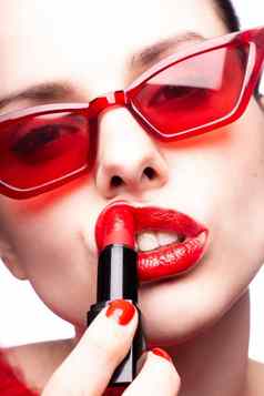 浅黑肤色的女人女人红色的太阳镜油漆嘴唇红色的口红红色的指甲白色背景