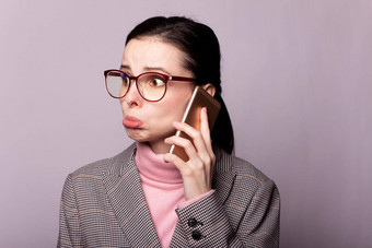 女人粉红色的高领毛衣灰色的夹克眼镜视线沟通电话灰色的背景