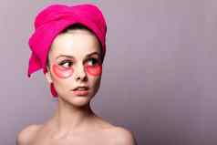 浅黑肤色的女人女人化妆品粉红色的补丁眼睛粉红色的毛巾头灰色的工作室背景特写镜头肖像