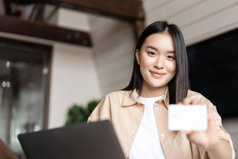 微笑亚洲女人坐着首页电脑显示信贷卡相机概念在线购物