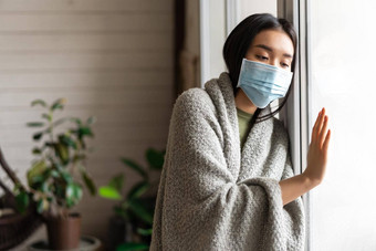 生病的亚洲女孩医疗脸面具站窗口向往检疫生病了科维德流感