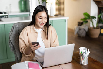 微笑亚洲女人移动PC<strong>首页</strong>女孩持有智能<strong>手机</strong>看网络研讨会电脑