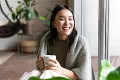 放松快乐亚洲女人舒适的衣服喝茶坐着窗口很高兴微笑