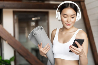 年轻的亚洲女人站首页耳机听音乐锻炼地板上席实践瑜伽冥想生活房间