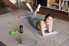 亚洲健身女孩打破锻炼锻炼首页地板上席哑铃蛋白质瓶瓶微笑相机