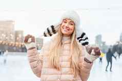 美丽的可爱的中年女孩金发女郎头发温暖的冬天夹克针织手套站冰溜冰场背景小镇广场圣诞节情绪生活方式