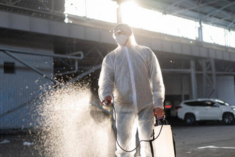 男人。穿着白色保护工作服喷涂表面抗菌洗手液喷雾器检疫